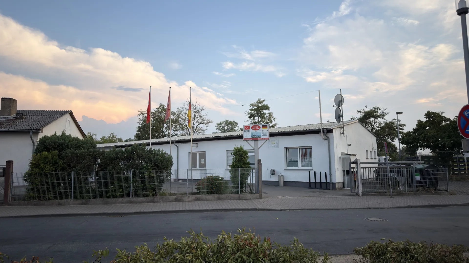 Binanın giriş bölümü: DITIB tabelası, bayrak direkleri ve çit
